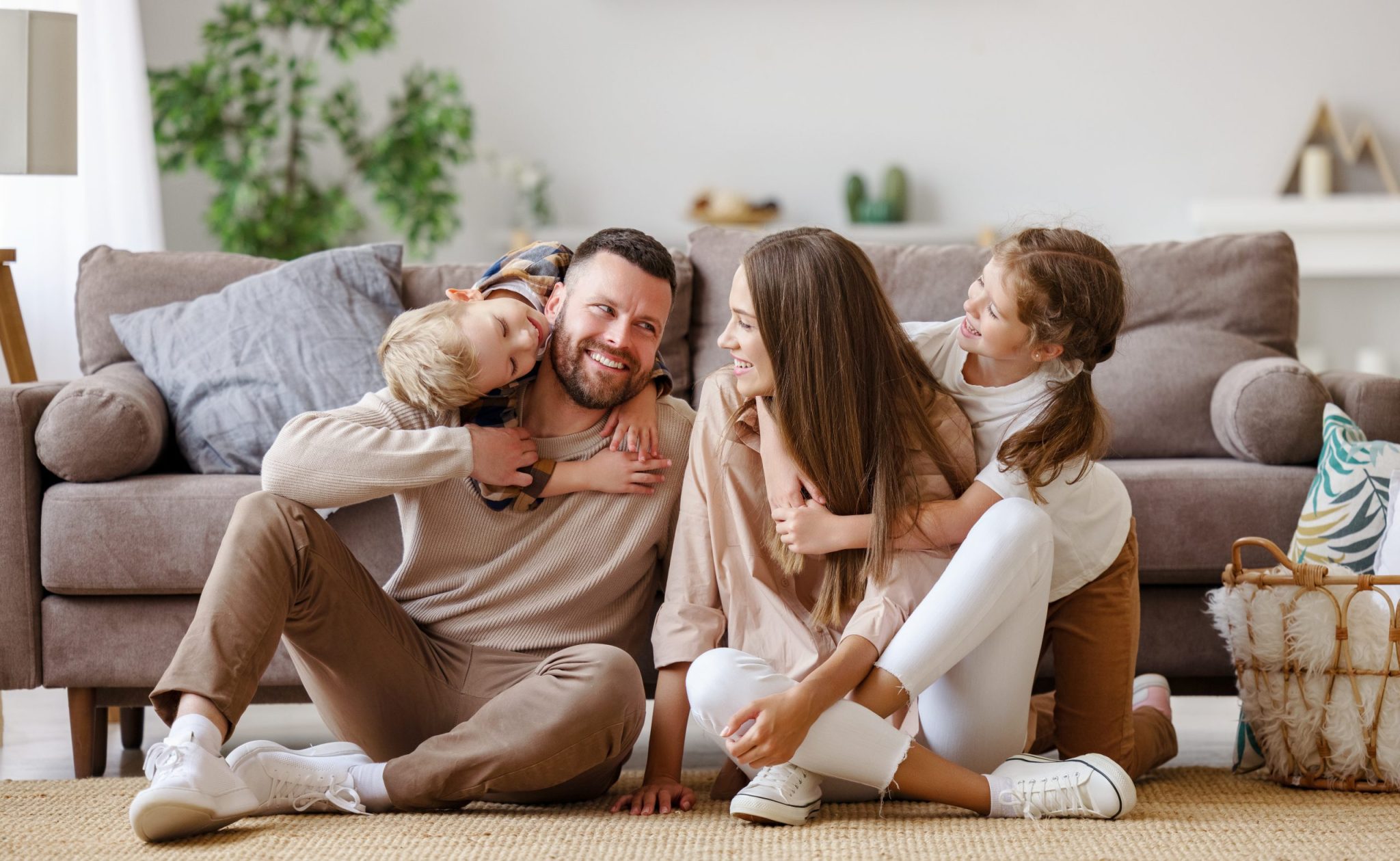 Happy Family Mother Father And Children At Home On Floor Next To Sofa